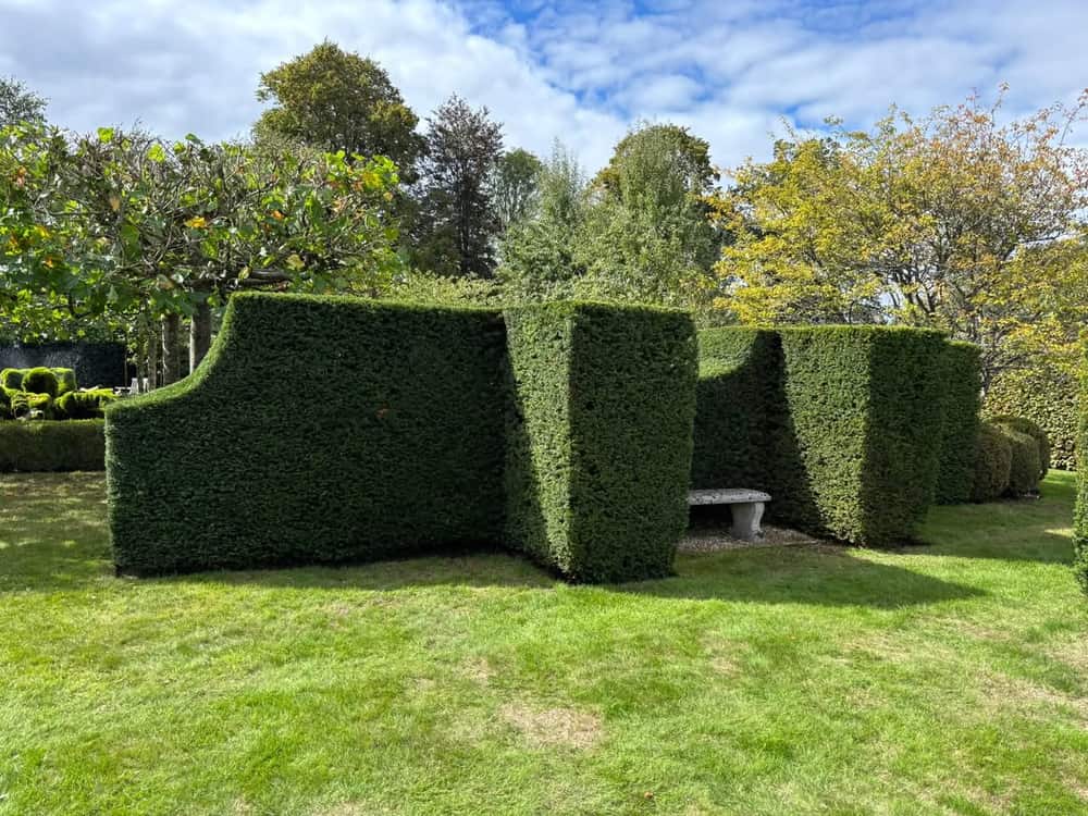 A stone seat set into a recess cut in a clipped hedge